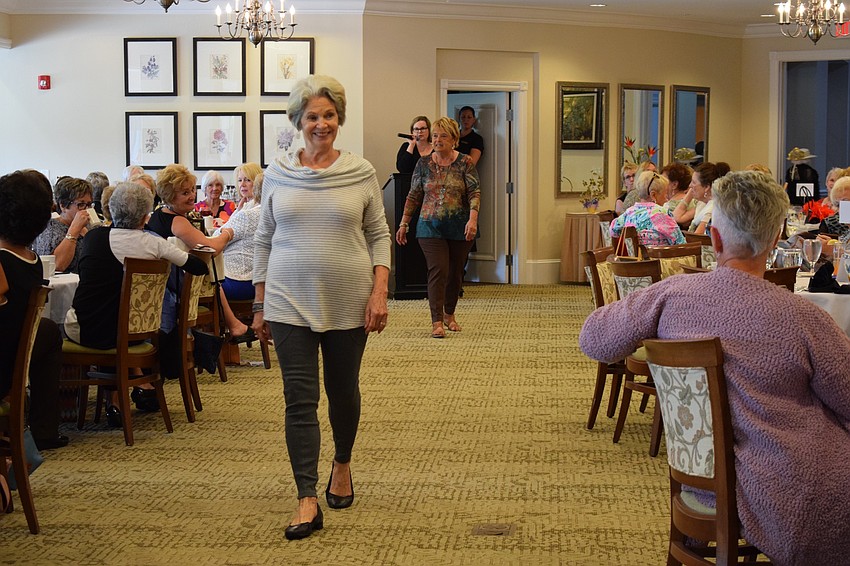 Tara resident Barbara Ehnes walks ahead of Bonnie Fuller as they go around the main dining room modeling clothes from Soft Surroundings. The fashion show benefited Manatee Children Services.