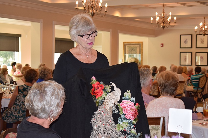 Donna Butler, a stock coordinator for Soft Surroundings, shows a verona sweater coat with an elegant embroidered peacock design to guests at the Tara Golf and Country Club fashion show.