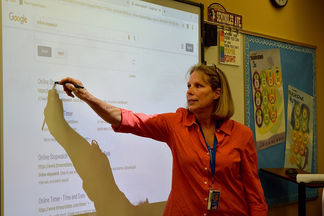 Linda Bryan-Beachler, a teacher at Freedom Elementary School, shows students how to access an online stopwatch for an experiment. File photo.