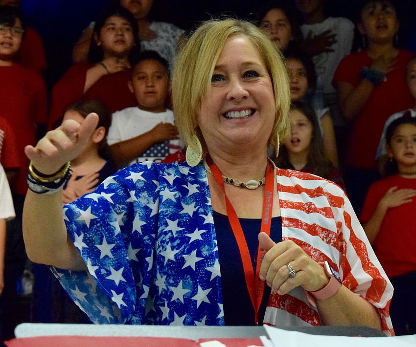 Music teacher Barbara Siffermann conducts students through the National Anthem.