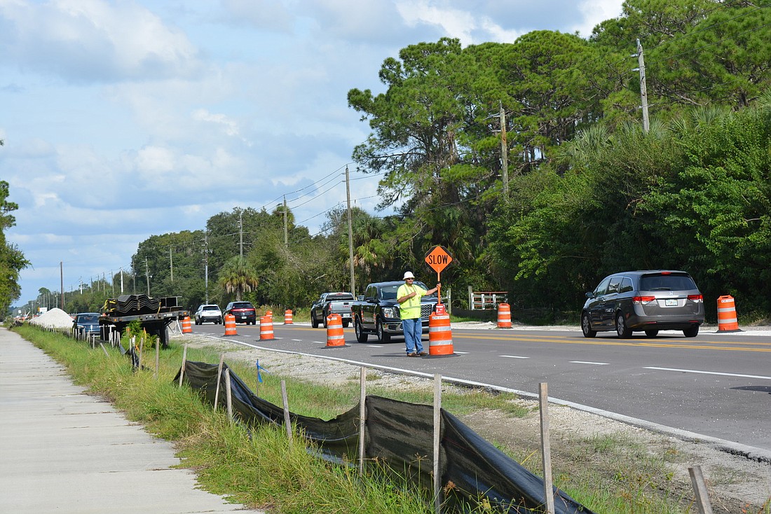 Contractors slow traffic as they complete work on Rye Road. Improvements include widening of the travel lanes and the addition of bicycle lanes and paved shoulder.