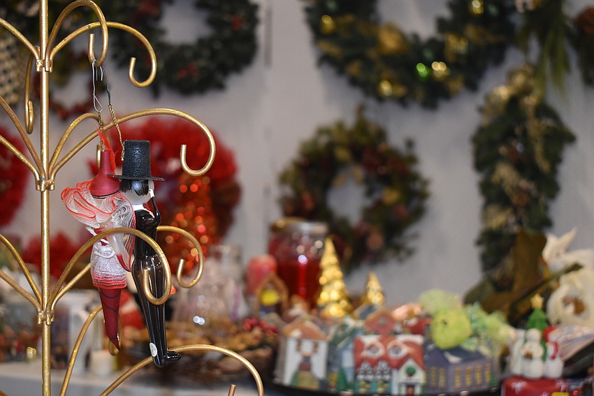 Two ornaments dance on a tree with piles of Christmas items in the background.