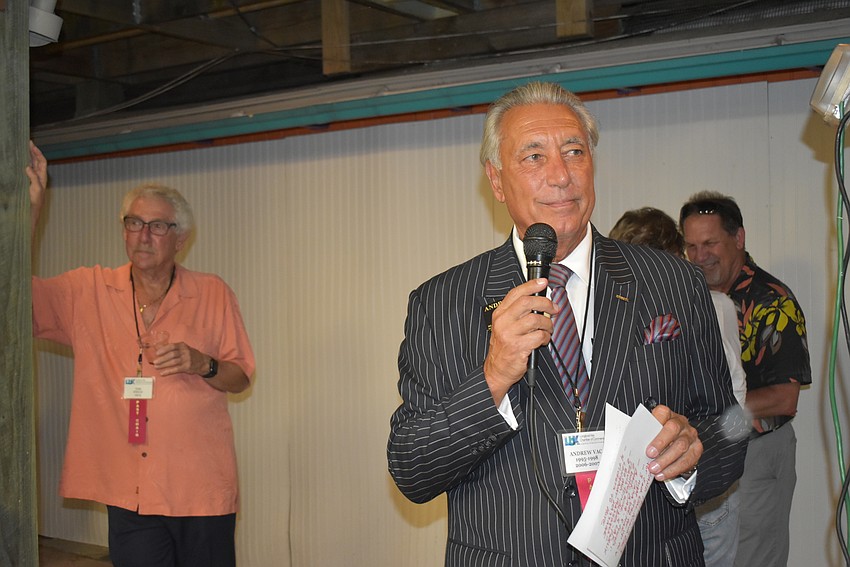 1975 chairman Tim Field stands in the background as 1995-1998/2006 chairman Andrew Vac introduces the event.