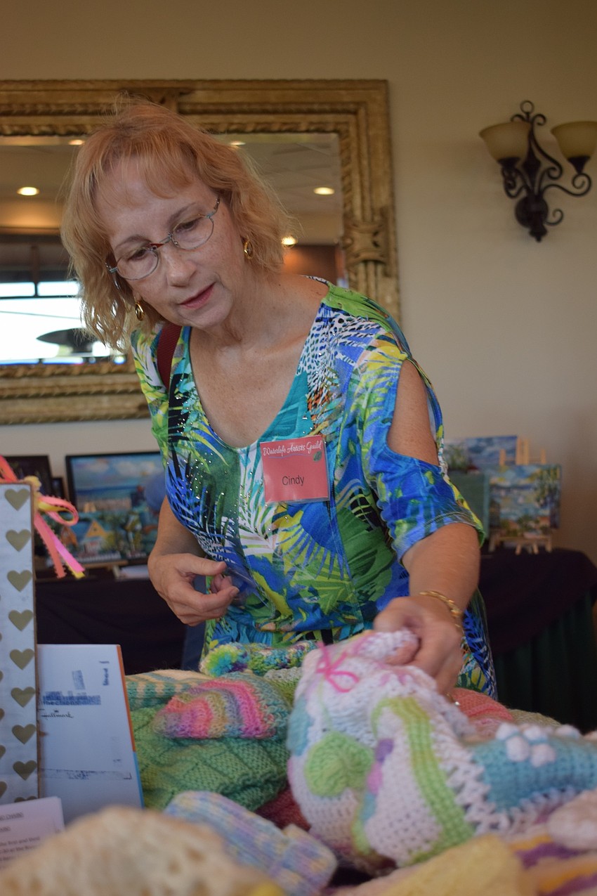Waterlefe resident Cindy Leadingham looks at different knitted and crocheted items from Purls and Chains, a group that makes items for charity. Leadingham also had a watercolor painting displayed in the show.