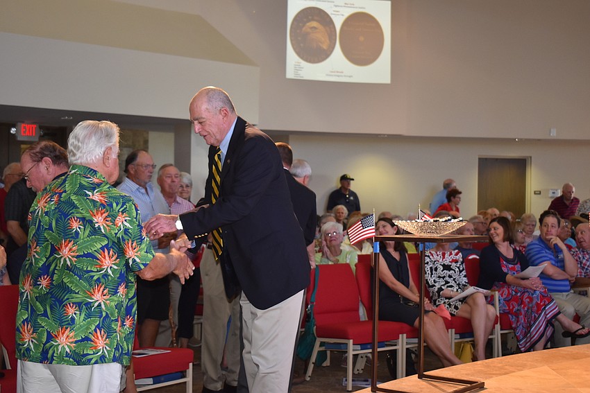 Stanley Minken gives a commemorative pin to a fellow Vietnam veteran.