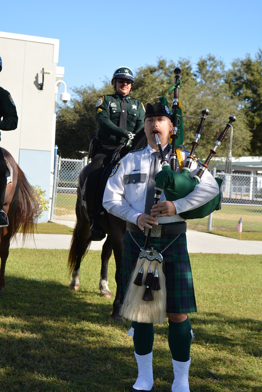 Manatee County Sheriff's Office detective Nate Boggs performs on the bagpipe as students file outside for the courtyard ceremony and flag-raising.