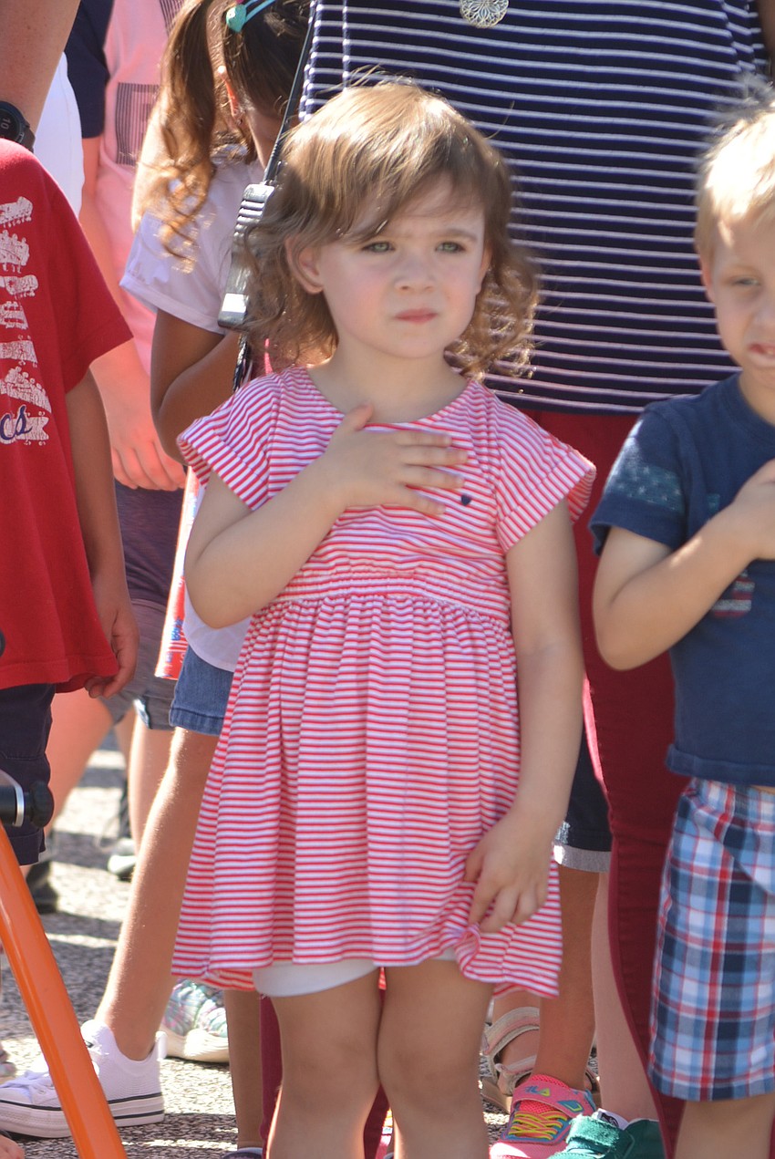 Pre-kindergartner Conner Amarosa puts her hand over her heart as the American flag is raised.