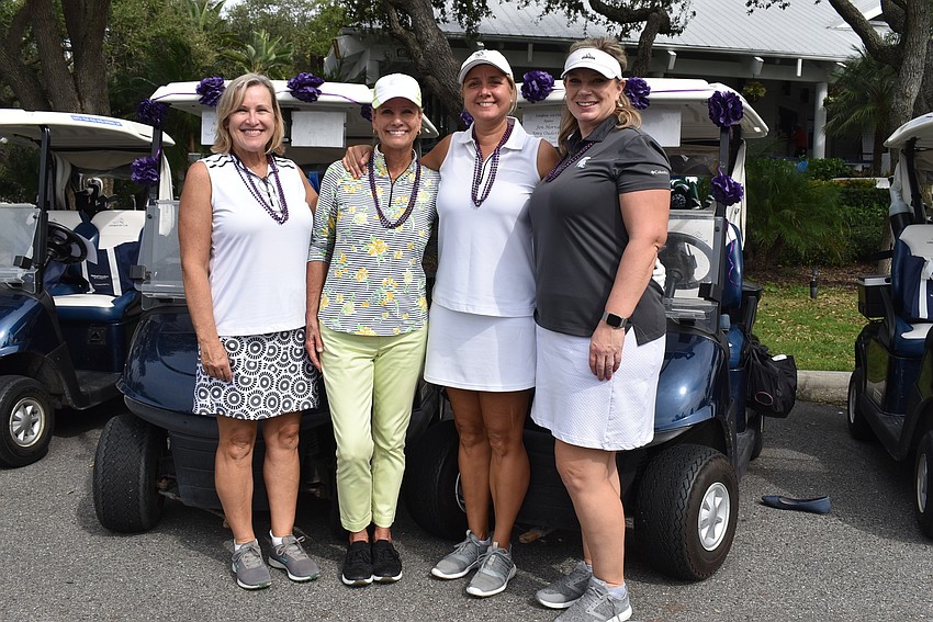 Katie Moulton, Laurie Zollinger, Jen Horvit and Amy Ouderkirk with their purple SPARCC-themed golf carts behind them.