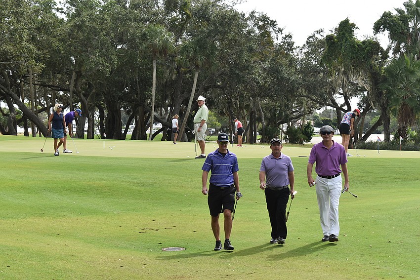 Golfers come off the putting green to get ready to start their games.