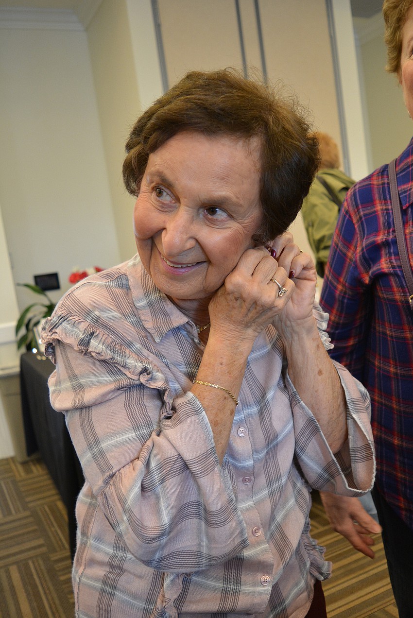 Palm Aire resident Judy Zinnamon tries on a pair of earrings made by Barby Cumins.