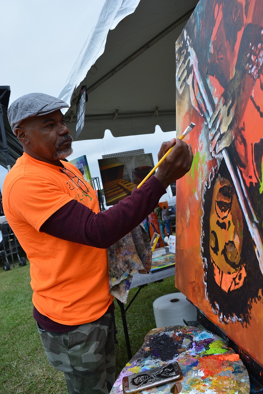 Artist Tom Ruthz paints an image of Jimmy Hendrix upside down.