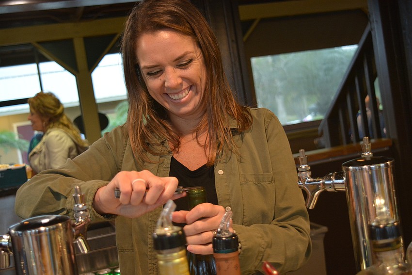 Sarasota Polo Club employee Kaitie Jones opens a bottle of Chardonnay to serve.