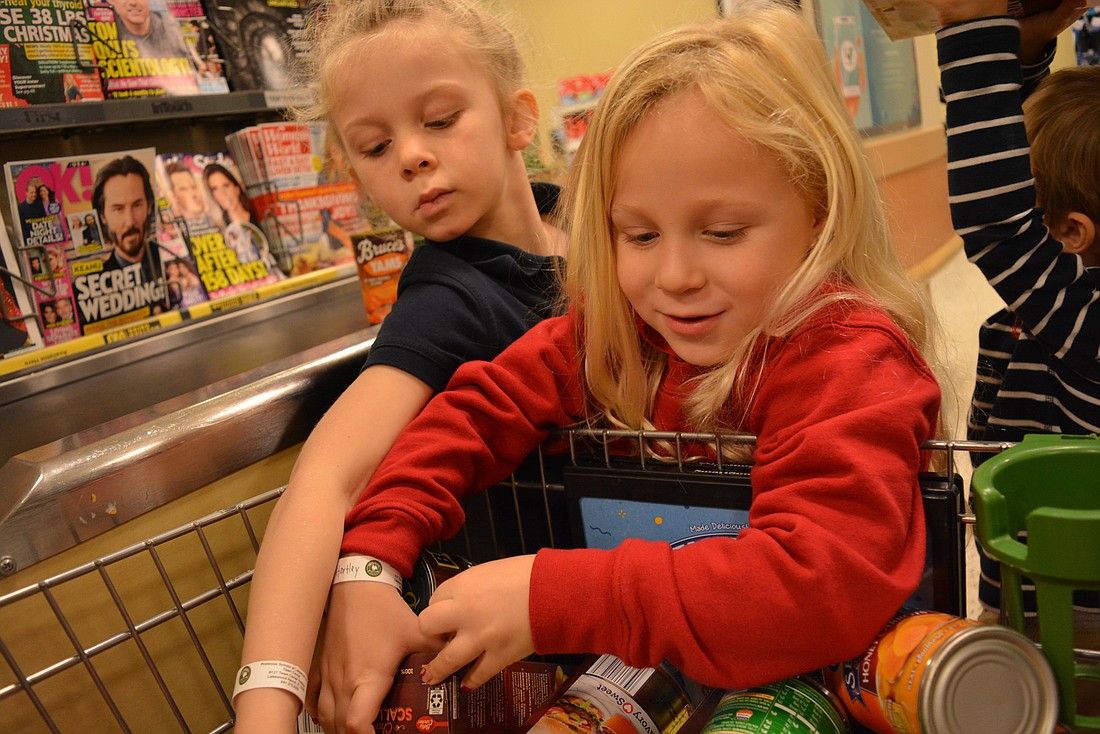 Wynn Watson and Hartley Aultman pull pasta, sauce, soup, stuffing, canned vegetables and other items from their cart after a busy morning of shopping. They found everything on their lists.