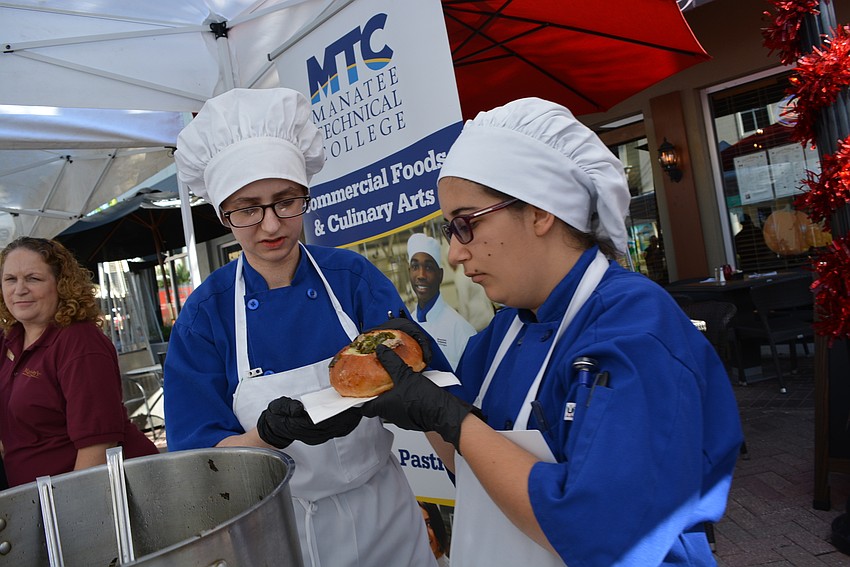 Manatee Technical College culinary students Yamile Soto and Elena Mata pour their zuppa toscana into a bread bowl for guests.