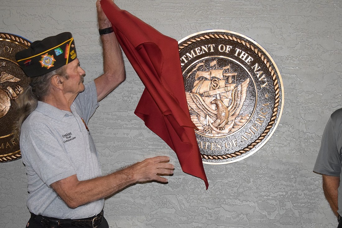 Graham Ellis, a Navy veteran and member of VFW Post 12055, slowly takes the cloth off the seal in honor of the Navy. Ellis&#39; daughter, Carly McCarthy, was an executive officer in Braden River High School&#39;s JROTC program in 2016.