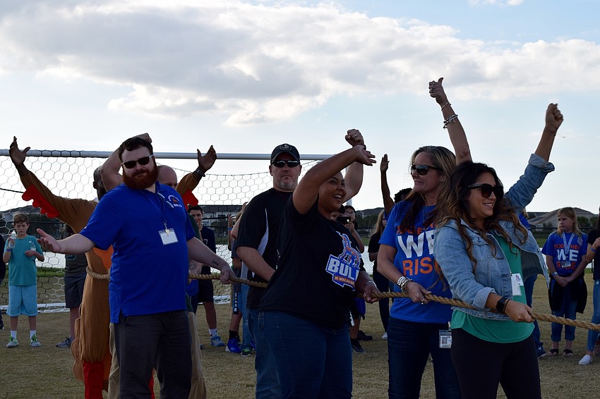Teachers and faculty members beam with confidence before facing a group of eighth graders in a tug of war.