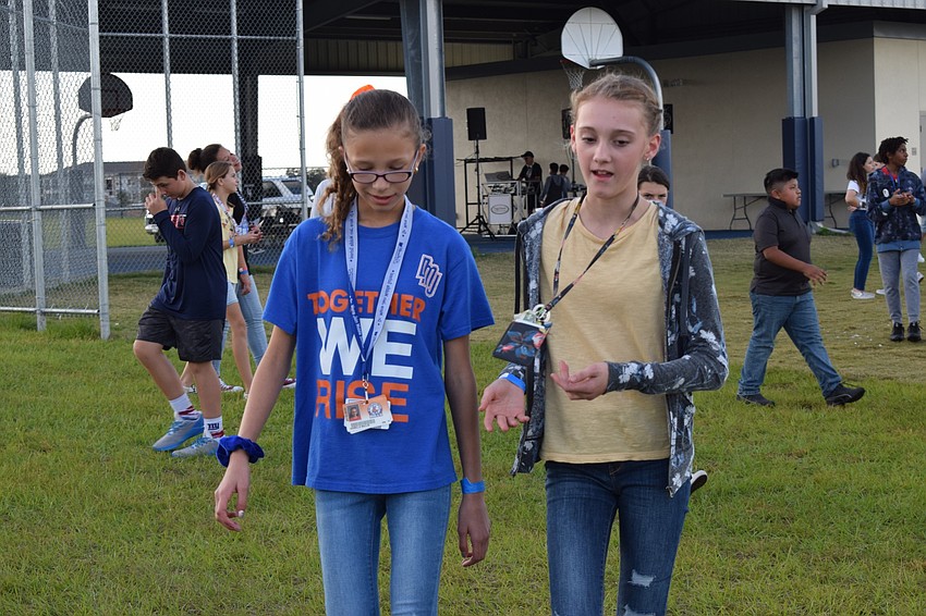 Isabella Mullis and Kenzie Hartmark, sixth-graders, walk together during the walk-a-thon. Hartmark said it was fun to listen to music and walk around.