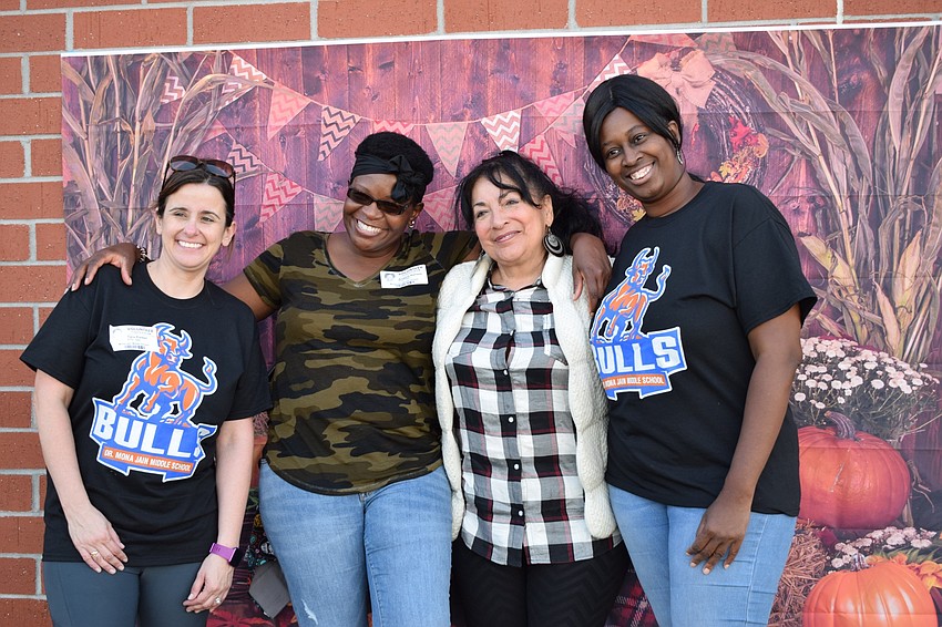 PTO members Tara Parker, Angel Kersey and Tamika Ward get a photo in front of a fall backdrop with ESE paraprofessional Miriam Ortiz.