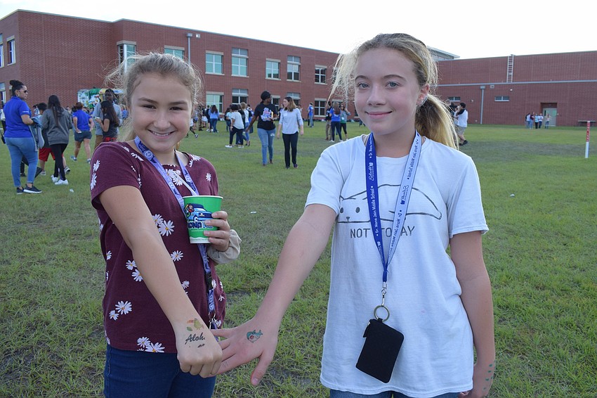 Olivia Autrey and Hana Pierce, sixth-graders, show off their temporary tattoos. Pierce chose a shark because her brother, Ethan, has a shark collection, and Autrey chose a parrot and 'Aloha' because it reminded her of the beach.