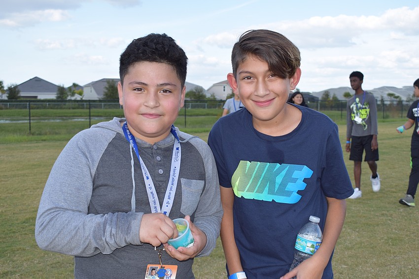 Henry Santos and Luis Martinez, sixth-graders, walk while enjoying Sidekicks, which are frozen flavored ice cups.