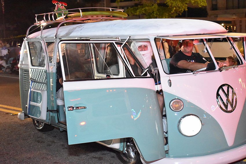 A vintage Volkswagen blasts holiday music through its open doors.