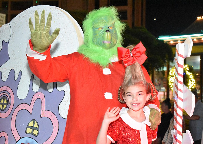 The Grinch and Cindy Lou Who wave to the crowd.
