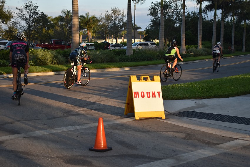 Cyclists take off after mounting their bikes in the triathlon.