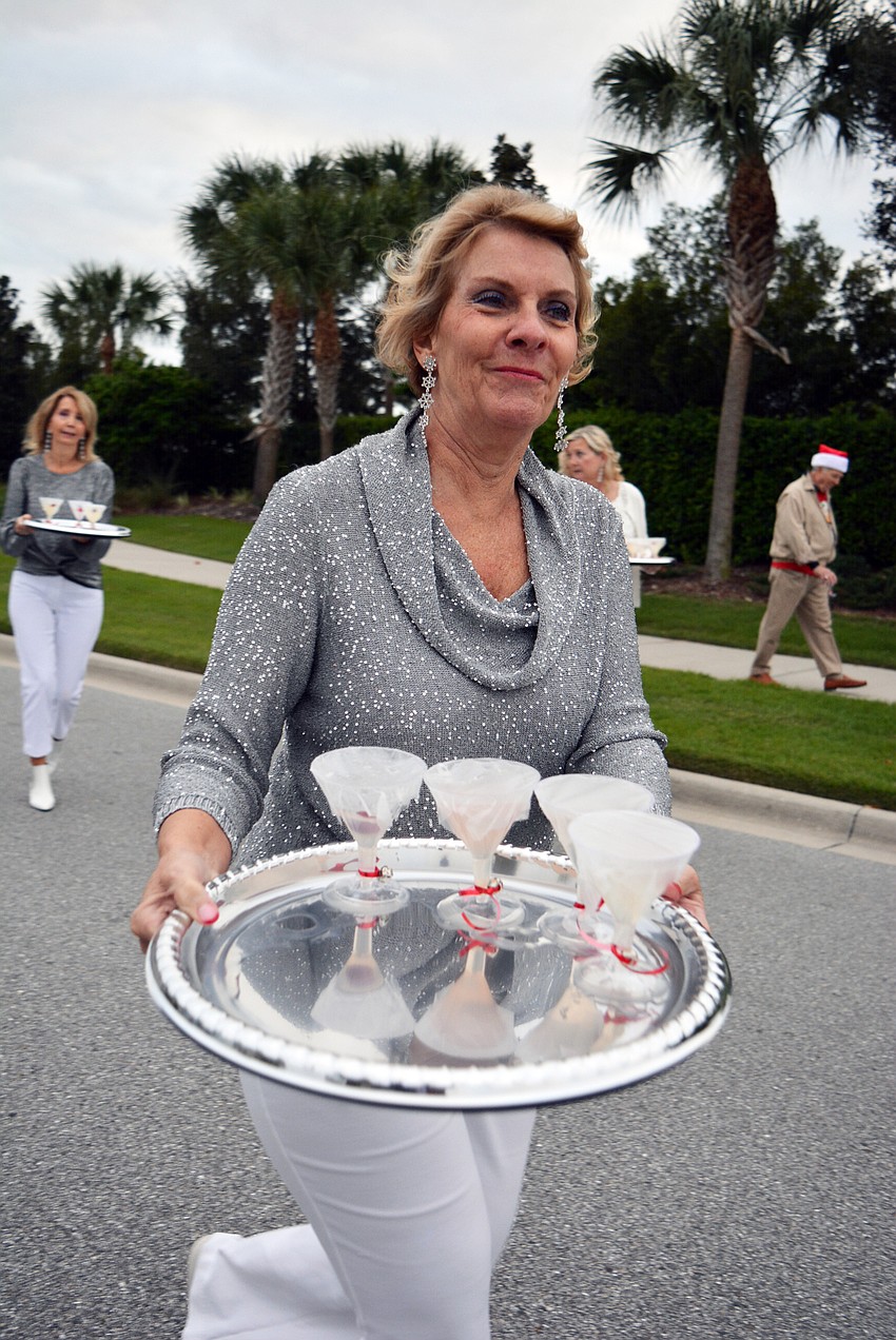 Merry Martini parade walker Shirley Hapner passes out prepared cranberry martinis to spectators who want them.