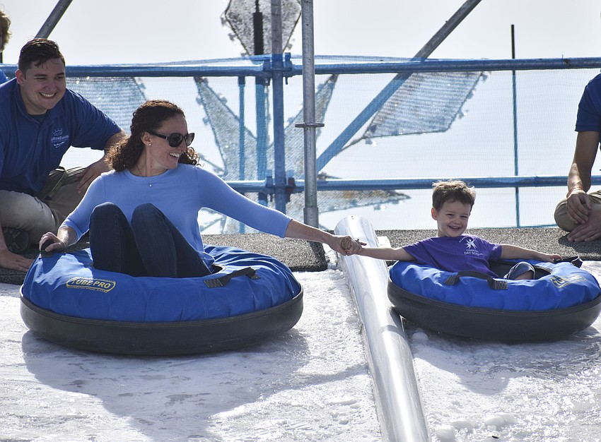 Jonathan Coca, manager of Ice Events, helps Shauna and Robby Wagner, 2, tube down the ice hill.