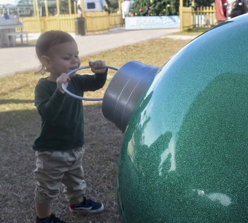 Jaxson Wilsen, 2, plays with the oversized ornament.