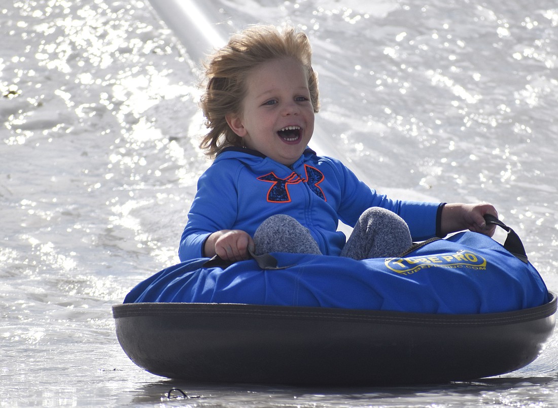 Kellan Letschert-Price, 4, laughs as he tubes down an ice slope at Holiday on the Green at University Town Center,