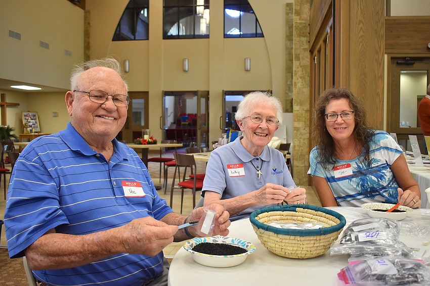 Vic and Kathy Englehardt and Sue Noppert fill seed packets.