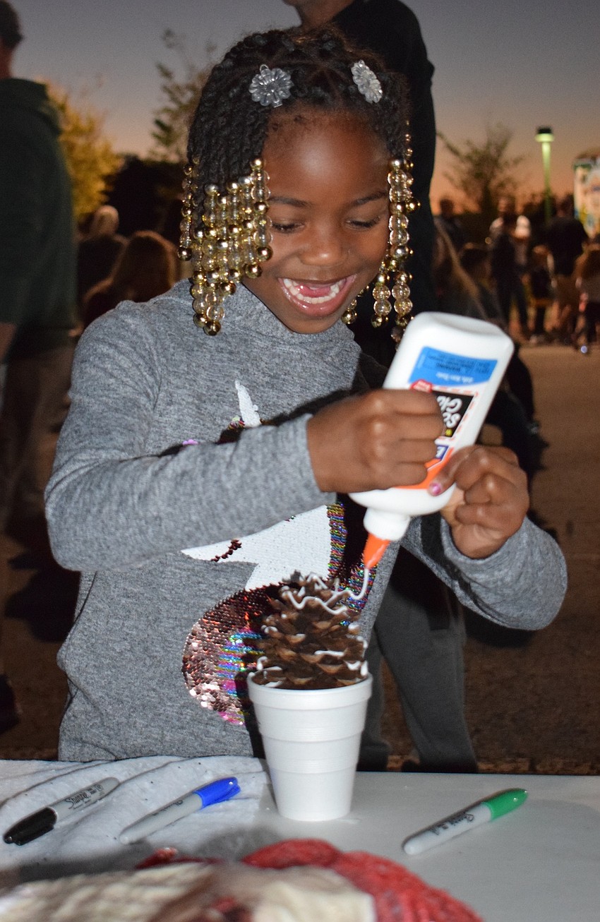 Kennedi Smith, 7, spreads glue over her reindeer pine cone before adding fake snow on top. Smith enjoyed going to the event because she loves crafts.