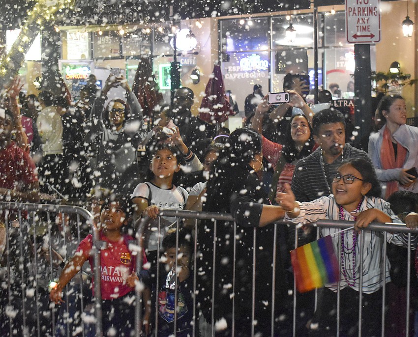 The crowd plays in the snow projected from the floats.