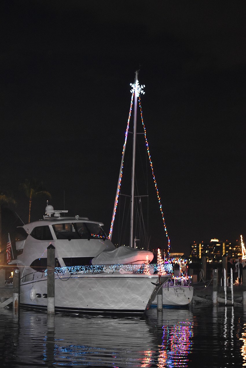 A triangular tree of lights rises from one boat.
