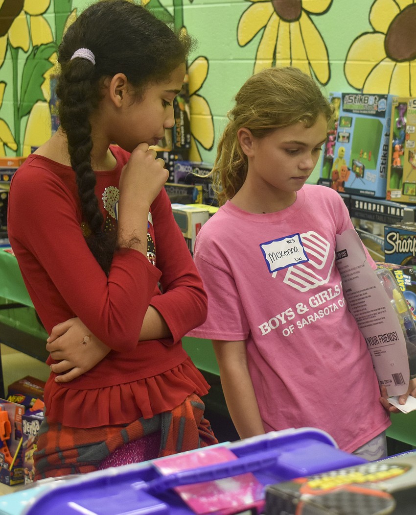 Amber Galva, 10, and Mckenna Herbster, 9, ponder the gifts table.