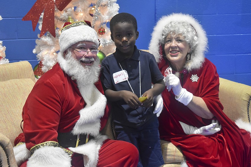 Marquis Deloach, 6, poses with Santa and Mrs. Claus.