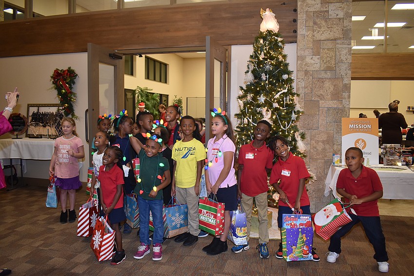 Children pose for a photo by the Christmas tree.