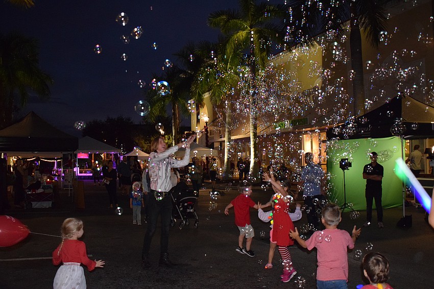 Kids run and jump around trying to pop bubbles.