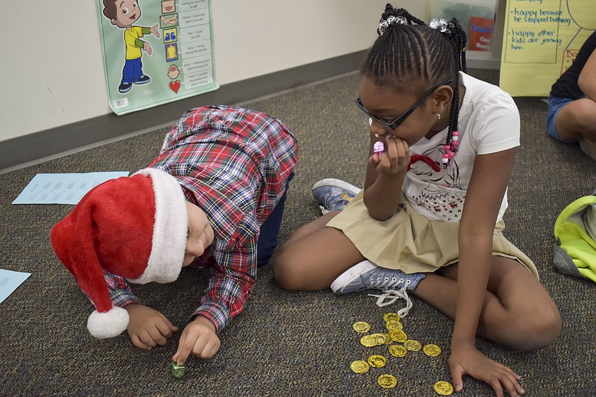 Ta'nyla Baskin watches intently as Caleb Berry spins his dreidel.