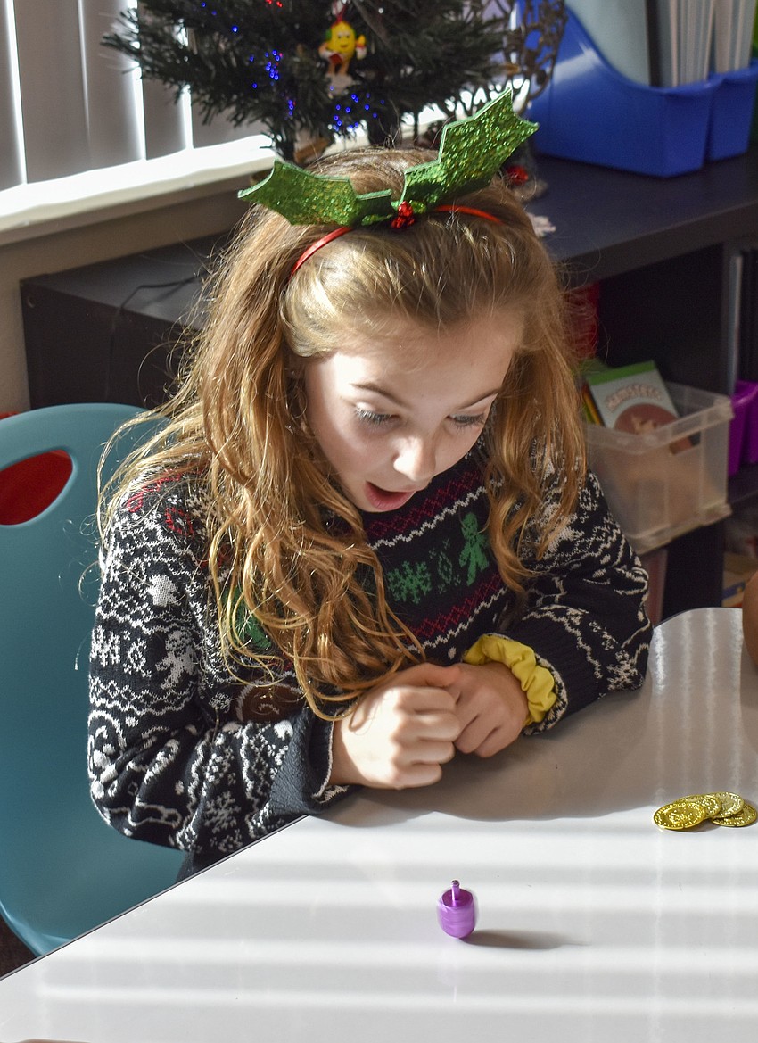 Violet Olson watches in amazement as her dreidel spins.
