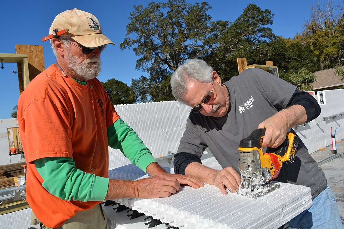 Habitat for Humanity Sarasota crew leader Mike Besselman helps Lake Club&#39;s Paul Lang cut an insulated concrete form to the right size.