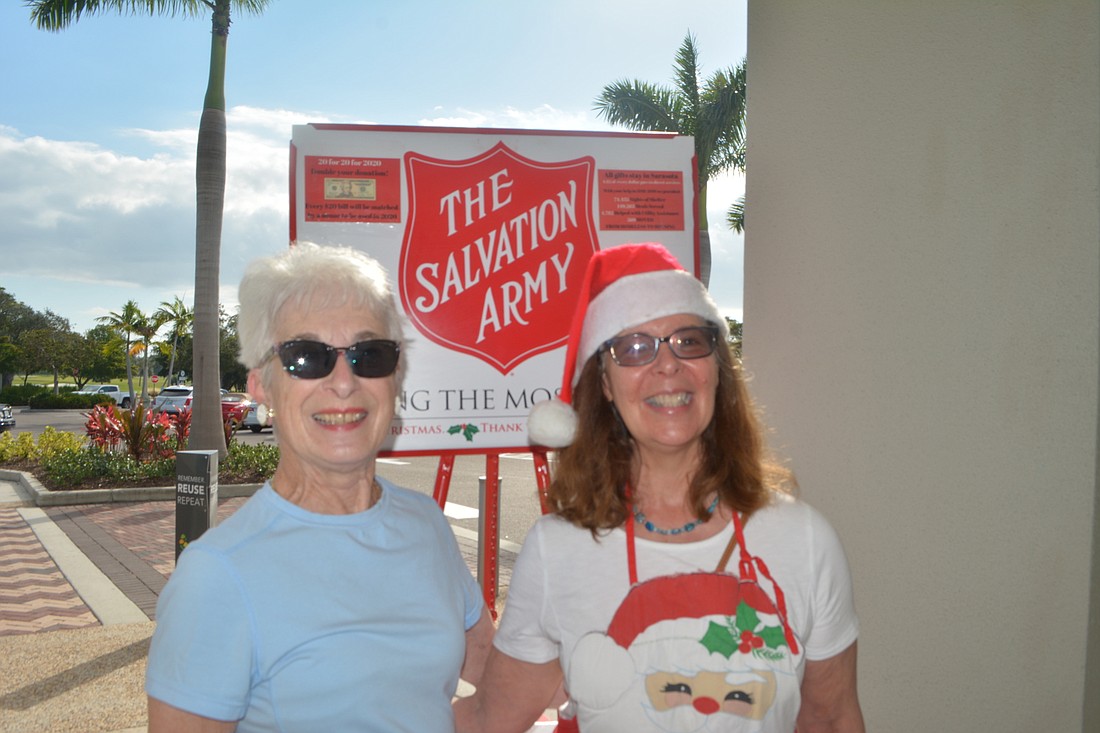 Pat Bentley stands with volunteer Beth Fusco in front of the red kettle this season.