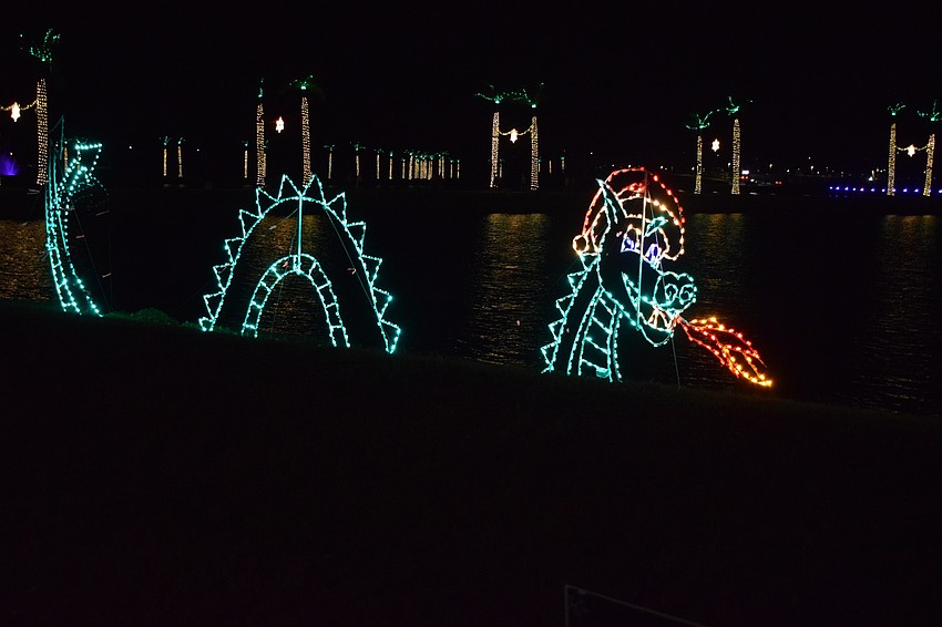 A light-up sea serpent blows fire into the lake. The serpent is one of dozens of light displays, which also included rowers, gifts and ice skaters.