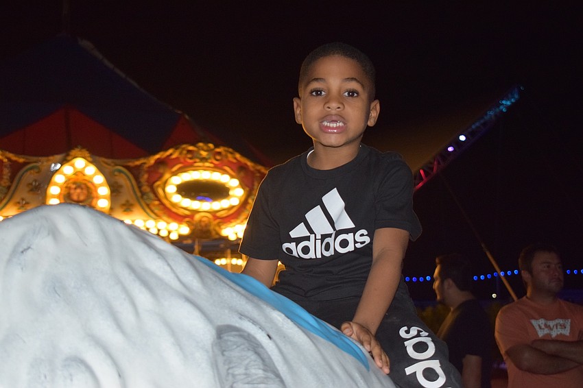 Sarasota's Jabari Olave Jr., 5, climbs on top of a buffalo painted white with colorful holiday lights. His mother, Latoya, said they wanted to go to Holidays on the Green one more time before it closes Jan. 6.