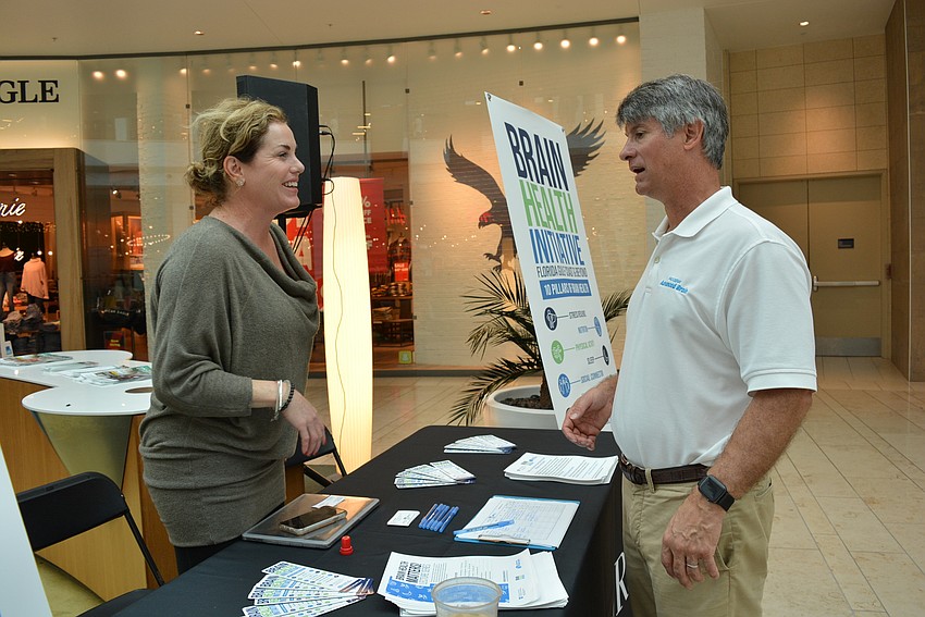 From her booth promoting the Brain Health Initiative, BHI  Program Director Kim Miele learns about  the Tampa-based brain health company, Procesa Health, from its CEO Scott Eibel.
