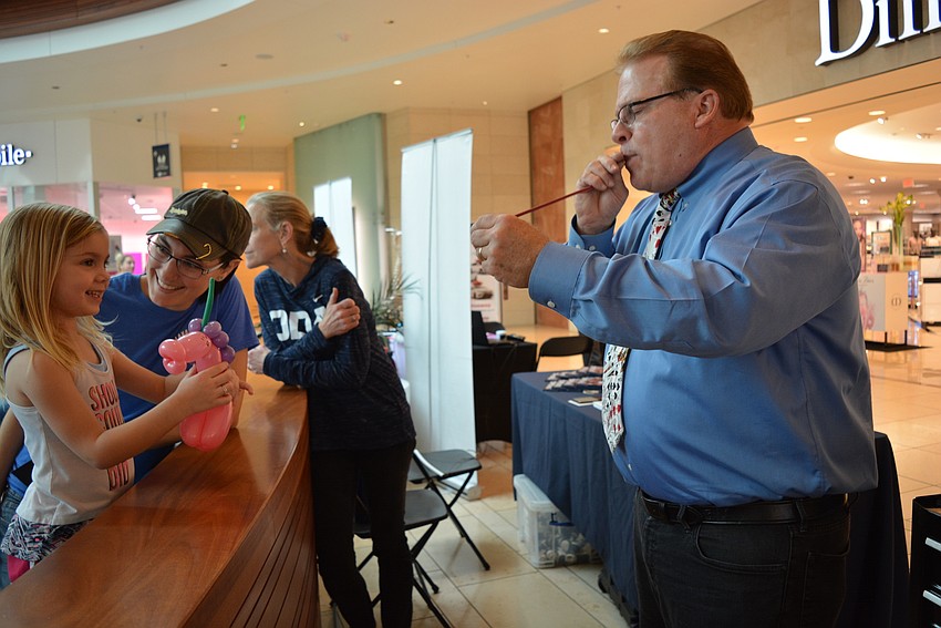 Three-year-old Addalyse Kuck, pictured with her mother, Brittany Kuck, gets a balloon unicorn and heart from balloon artist Mike Jones.