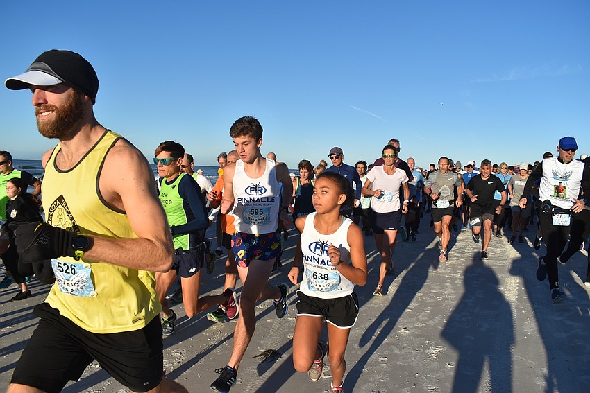 Runners stream down the beach in a colorful stampede.