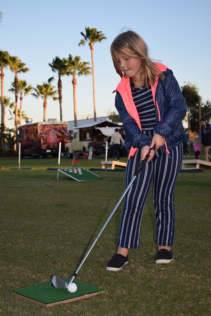 Lakewood Ranch's Sanibel Sibner, 7, attempts to hit a golf ball into a cup. Miniature golf games were just one of the yard games available for people to play at the first Ranch Nite Wednesday.