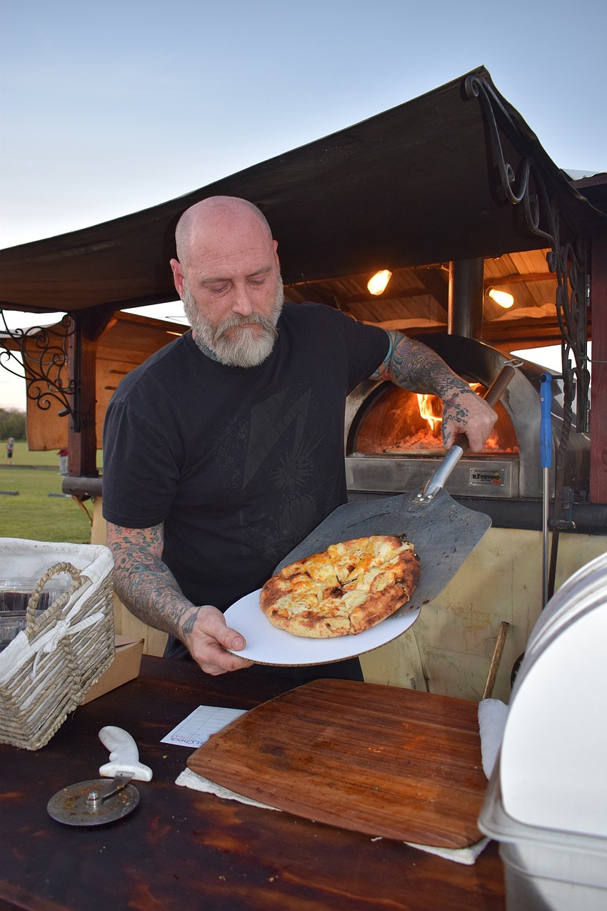 Ryan Kelly, the executive chef with Cornerstone and Co., finishes preparing a pizza for a customer. The Cornerstone and Co. was one of at least seven food trucks at Ranch Nite Wednesday.